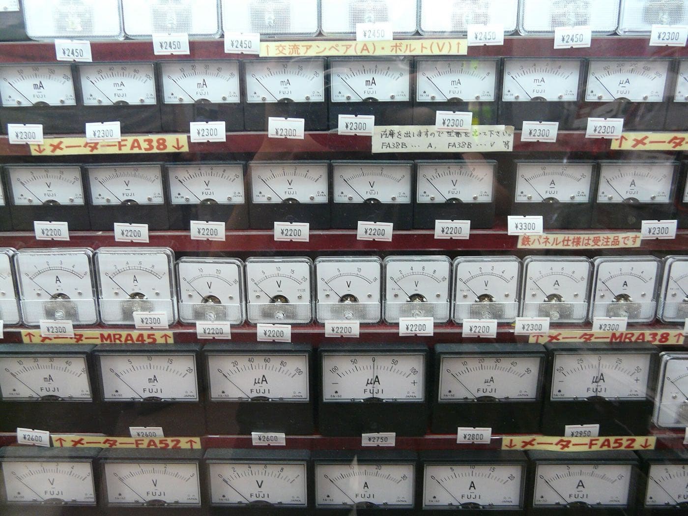 Wall of analogue voltmeters and ammeters with handwritten price tags