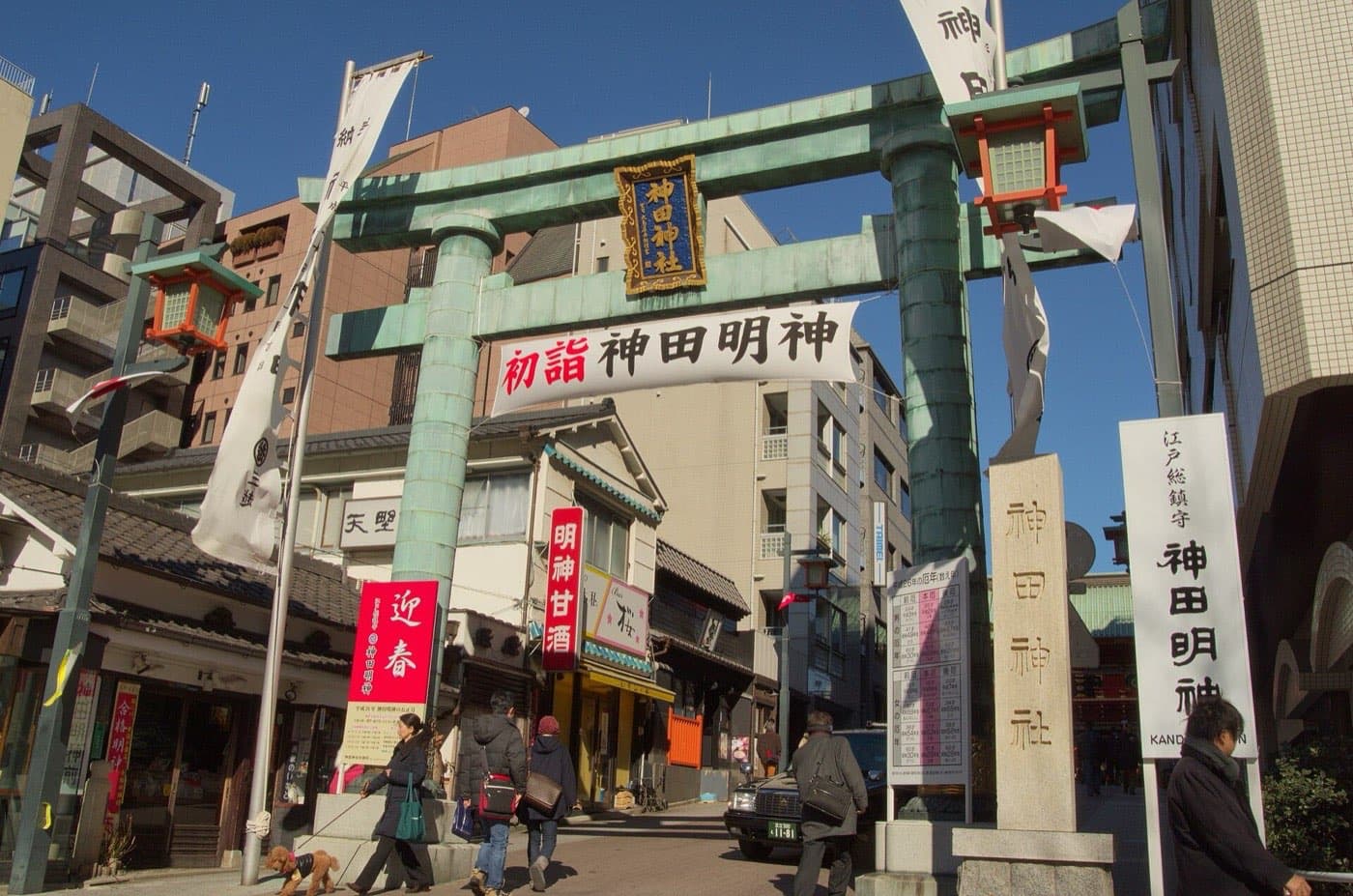 Bronze torii gate of Kanda Shrine with a white banner and red New Year signs